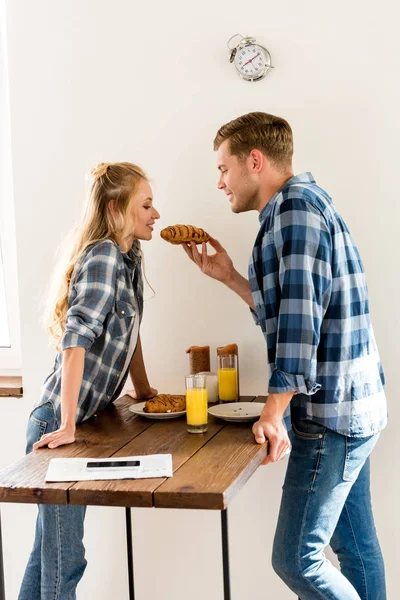 Vista lateral do jovem casal tomando café da manhã na cozinha em casa — Fotografia de Stock