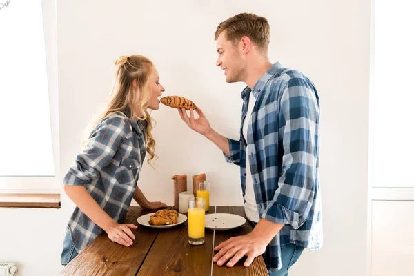 Side view of young couple having breakfast in kitchen at home — Stock Photo