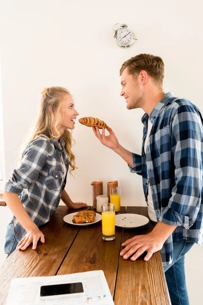 Вид сбоку на молодую пару, завтракающую на кухне дома — стоковое фото