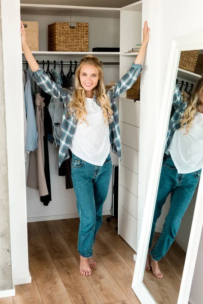 Smiling woman standing at wardrobe at home — Stock Photo