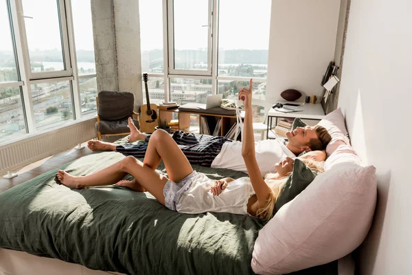 Side view of young couple in love in pajamas lying on bed in morning — Stock Photo
