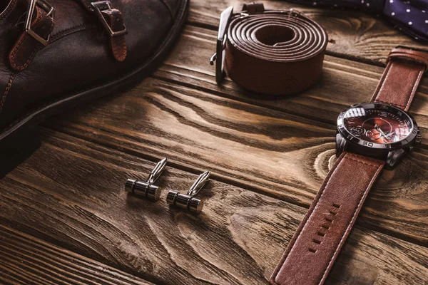 Закрытый вид на кожаные мужские аксессуары и обувь, расположенные на деревянном столе — стоковое фото