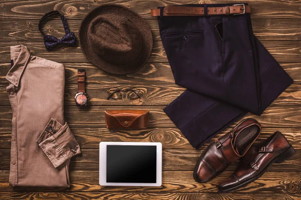 Tendido plano con ropa masculina, accesorios y tableta digital dispuestos en la superficie de madera - foto de stock