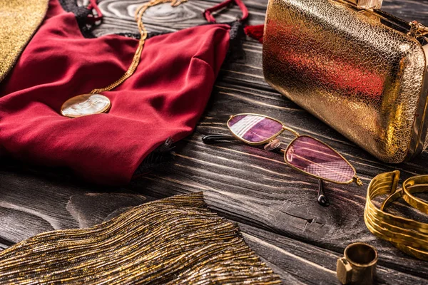 Close up view of arrangement of golden and red fashionable feminine accessories and clothing on wooden surface — Stock Photo