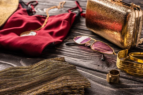 Vista ravvicinata di disposizione di accessori femminili alla moda d'oro e rossi e vestiti su superficie di legno — Foto stock