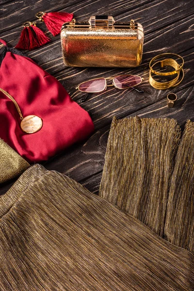 Nahaufnahme der Anordnung von goldenen und roten modischen femininen Accessoires und Kleidungsstücken auf Holzoberfläche — Stockfoto