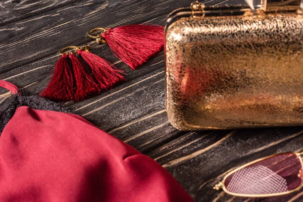 Vista de perto da bolsa feminina vermelha e dourada na moda e earrigns na mesa de madeira — Fotografia de Stock