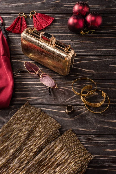 Vista de cerca de accesorios femeninos rojos y dorados en la superficie de madera - foto de stock