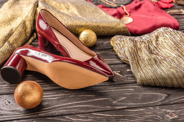 Vista da vicino di belle scarpe rosse femminili e abbigliamento elegante sulla superficie di legno — Foto stock