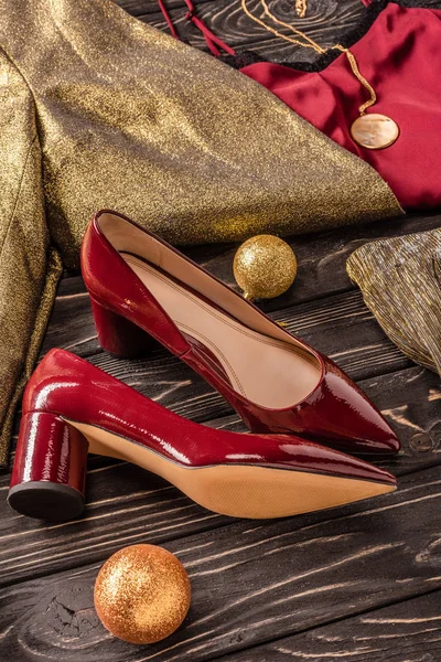 Vista de perto de belos sapatos vermelhos femininos e roupas elegantes na superfície de madeira — Fotografia de Stock