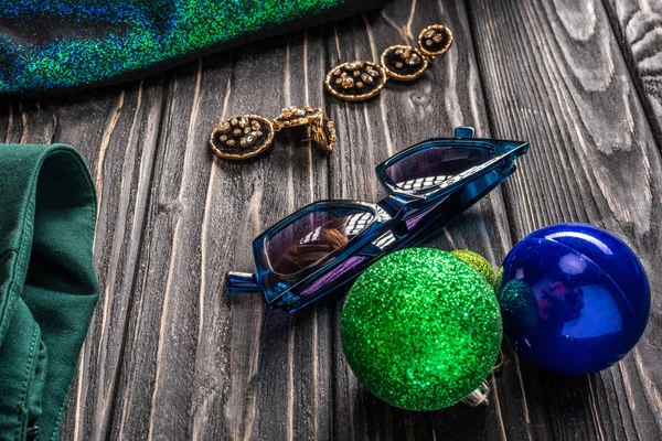 Close up view of  stylish sunglasses, earrings and christmas balls on wooden tabletop — Stock Photo