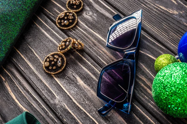 Close up view of stylish sunglasses and earrings on wooden tabletop — Stock Photo