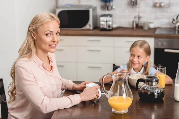 Счастливые молодая мать и дочь завтракают вместе на кухне — стоковое фото
