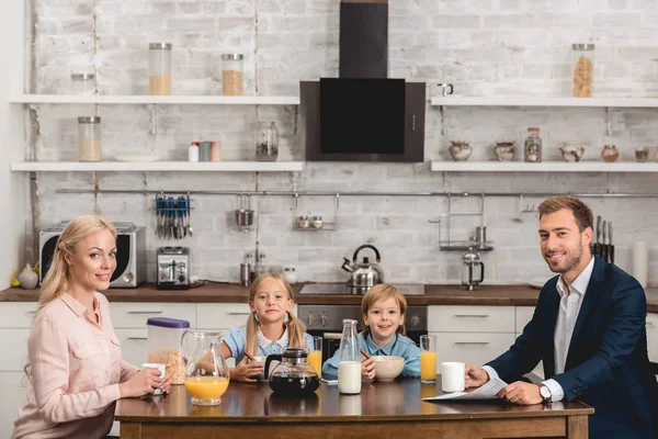 Hermosa familia joven desayunando juntos en la cocina - foto de stock