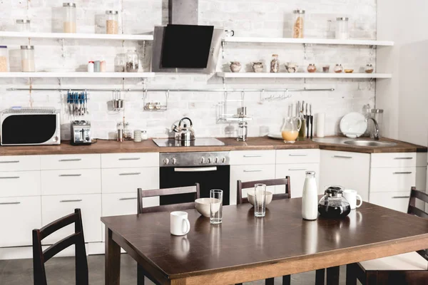 Interior de la moderna cocina blanca con mesa lista para el desayuno - foto de stock