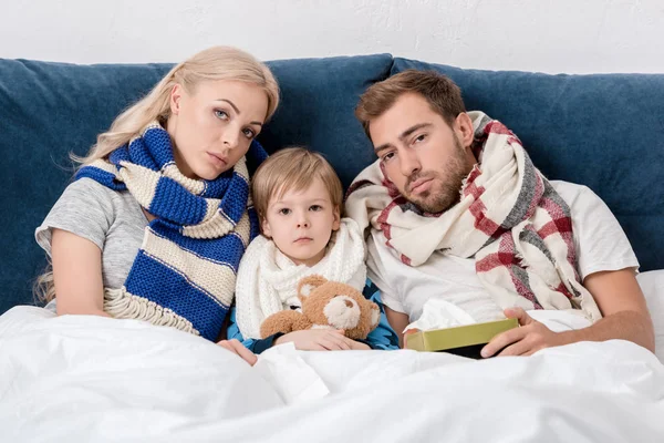 Больные родители и сын сидят в постели и смотрят в камеру — стоковое фото