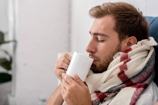 Ritratto ravvicinato del giovane malato in sciarpa con tazza di tè — Foto stock