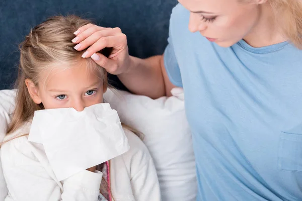 Close-up shot of mother taking care of her daughter while she blowing nose — Stock Photo