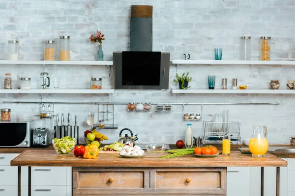 Varias verduras crudas en la mesa en la cocina moderna - foto de stock