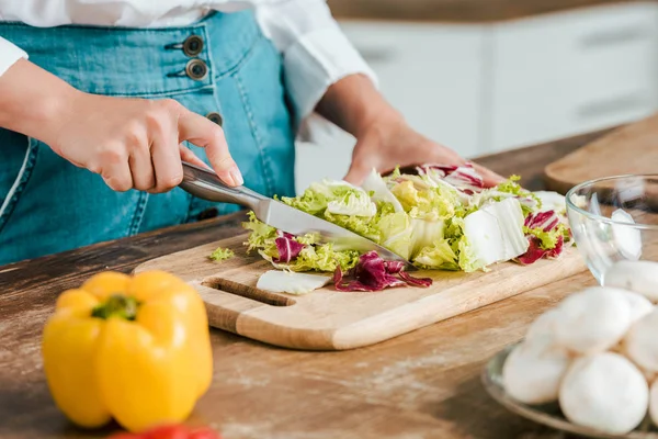 Colpo ritagliato di donna taglio lattuga per insalata sul tagliere di legno — Foto stock