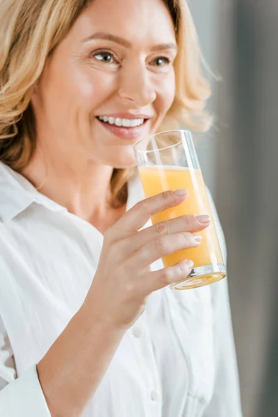 Primer plano retrato de hermosa mujer adulta bebiendo jugo de naranja - foto de stock