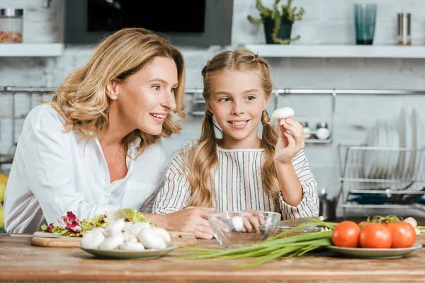 Mãe e filha olhando para cogumelo juntos enquanto cozinham — Fotografia de Stock