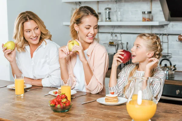 Glückliche drei Generationen von Frauen mit Pfannkuchen und gesunden Äpfeln zum Frühstück zu Hause — Stockfoto