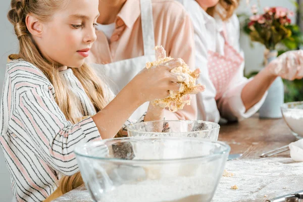 Cropped shot of adorable little child making dough with parents at home — Stock Photo
