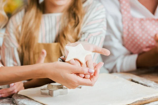 Cropped shot of child and woman holding star shaped piece of dough — Stock Photo