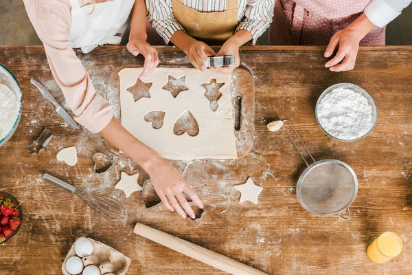 Recortado de tres generaciones de mujeres preparando galletas de Navidad en casa y mirando a la cámara - foto de stock