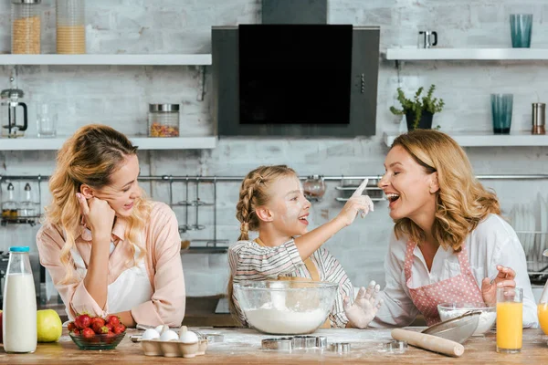 Lächelndes kleines Kind bereitet Teig zu und spielt mit Mutter und Großmutter zu Hause — Stockfoto