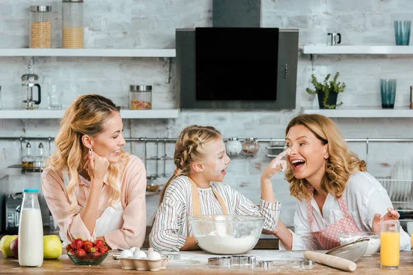 Glückliches kleines Kind bereitet Teig zu und spielt mit Mutter und Großmutter zu Hause — Stockfoto