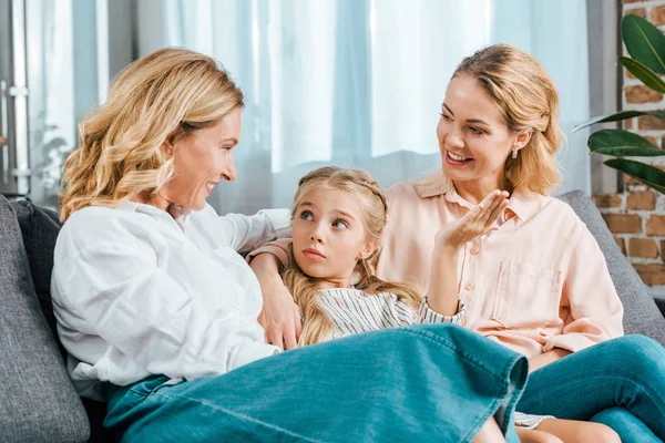 Bambino felice con mamma e nonna sedute sul divano a casa — Foto stock