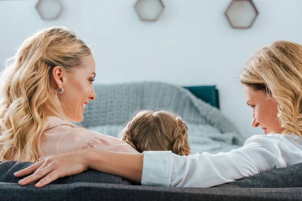 Rear view of child with mother and grandmother sitting on couch at home — Stock Photo