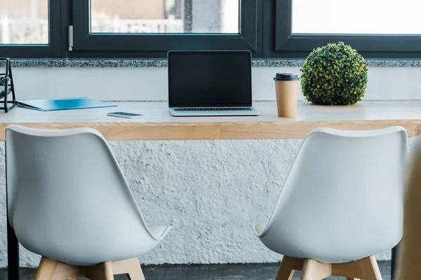 Ordinateur portable avec écran vierge et tasse à café jetable sur une table en bois au bureau — Photo de stock