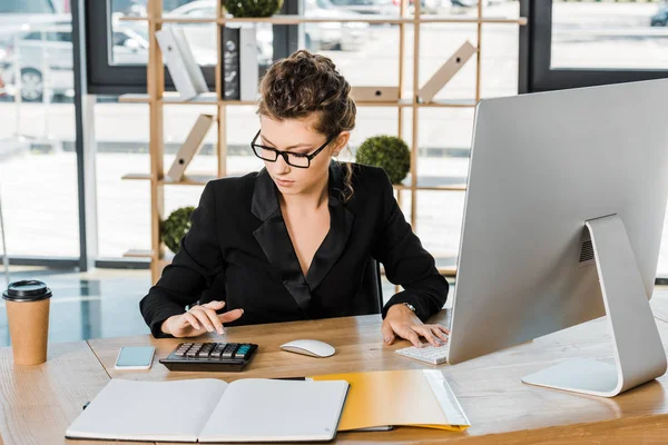 Attraente donna d'affari che lavora e utilizza la calcolatrice con il computer in ufficio — Foto stock