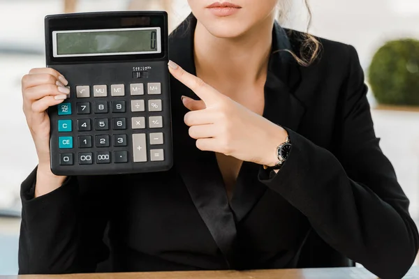 Cropped image of businesswoman pointing on calculator in office — Stock Photo