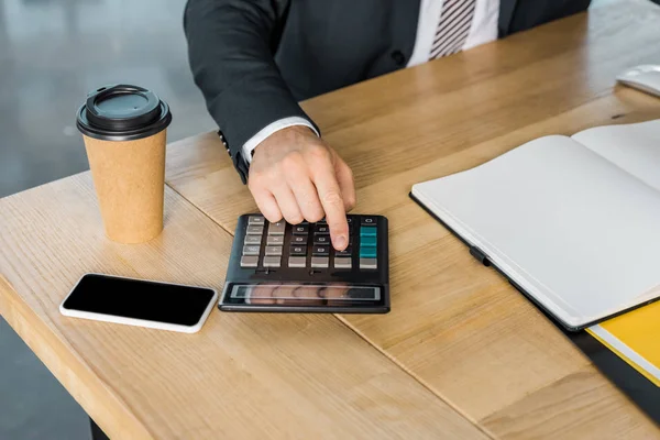Immagine ritagliata di uomo d'affari utilizzando la calcolatrice durante il lavoro in ufficio — Foto stock