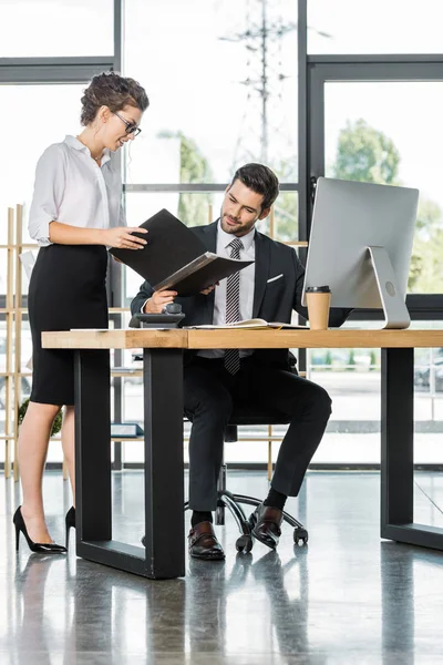 Attractive businesswoman showing folder with documents to businessman in office — Stock Photo