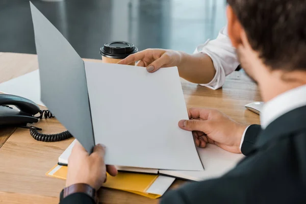 Partial view of businesswoman and business partner with papers discussing work at workplace in office — Stock Photo