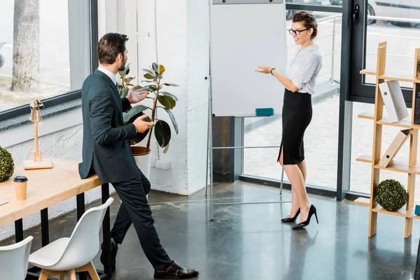 Joven hombre de negocios y mujer de negocios discutiendo el plan de negocios durante la reunión en el cargo - foto de stock