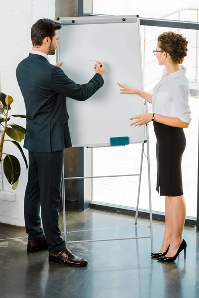 Young businessman and businesswoman discussing business plan during meeting in office — Stock Photo