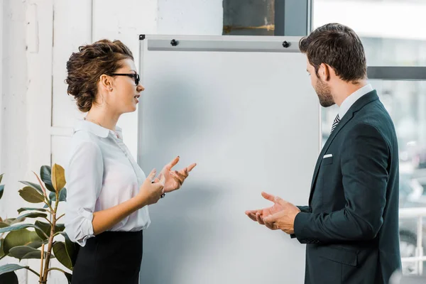 Side view of business colleagues discussing work at blank white board in office — Stock Photo
