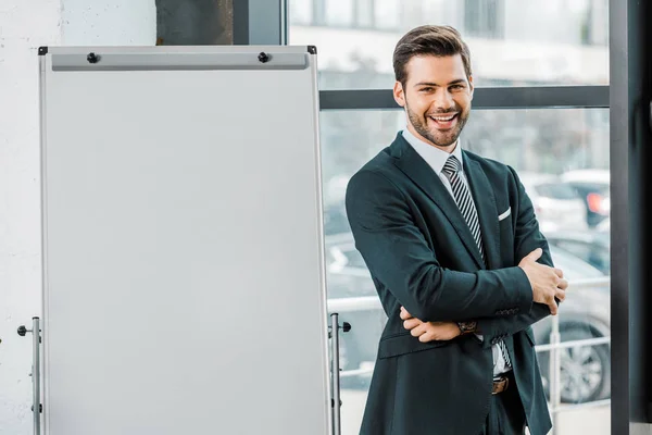 Portrait de sourire \businessman en costume debout au tableau blanc vide au bureau — Photo de stock