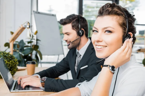 Vista lateral de operadores de call center sorridentes no local de trabalho no escritório — Fotografia de Stock
