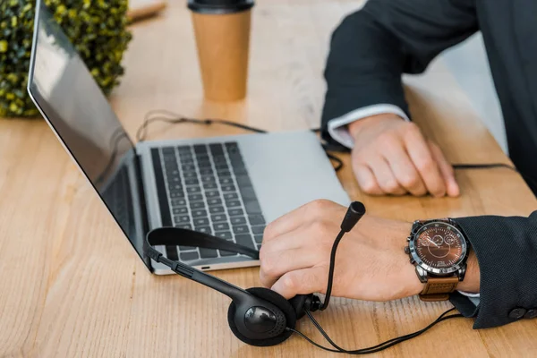 Cropped shot of call center operator at workplace with laptop and headset in office — Stock Photo