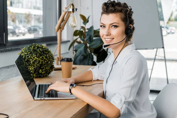 Jovem sorrindo operador de call center feminino com fone de ouvido no local de trabalho no escritório — Fotografia de Stock