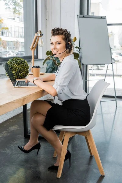 Operador de centro de llamadas femenino joven con auriculares en el lugar de trabajo en la oficina - foto de stock