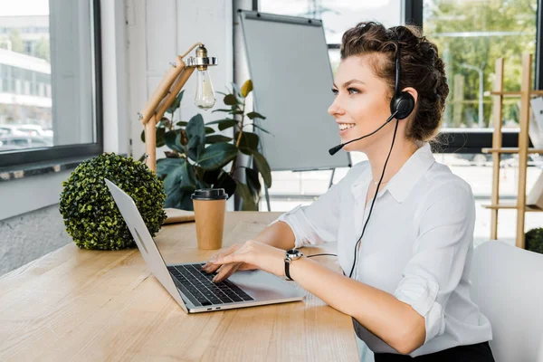 Opératrice de centre d'appels souriante avec casque sur le lieu de travail au bureau — Photo de stock