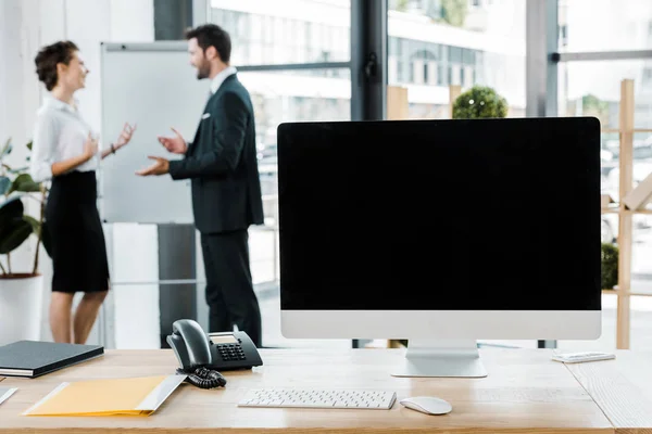 Foco seletivo de colegas de negócios discutindo o trabalho no quadro branco e tela do computador em branco na mesa no escritório — Fotografia de Stock